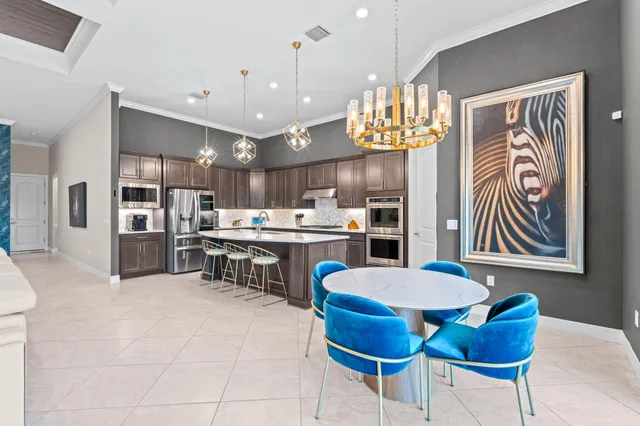 a kitchen with a refrigerator a sink dishwasher a dining table and chairs with wooden floor