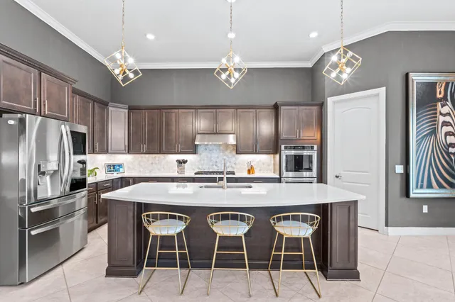 a kitchen with kitchen island granite countertop a table chairs refrigerator and microwave