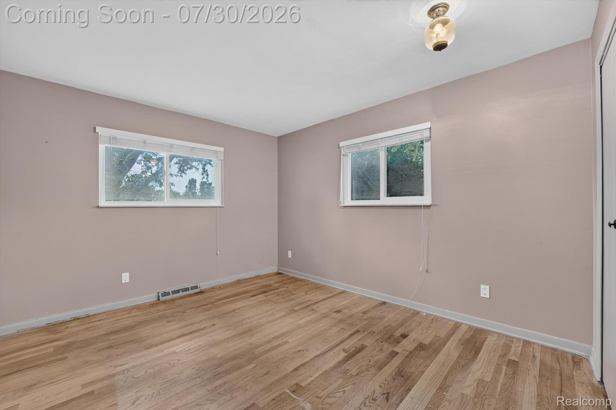 5991 Maybee Road Clarkston, MI 48346 - Photo 14 of 41 Room featuring wood-finish flooring, two windows, painted walls, ceiling-mounted light fixture, and white trim