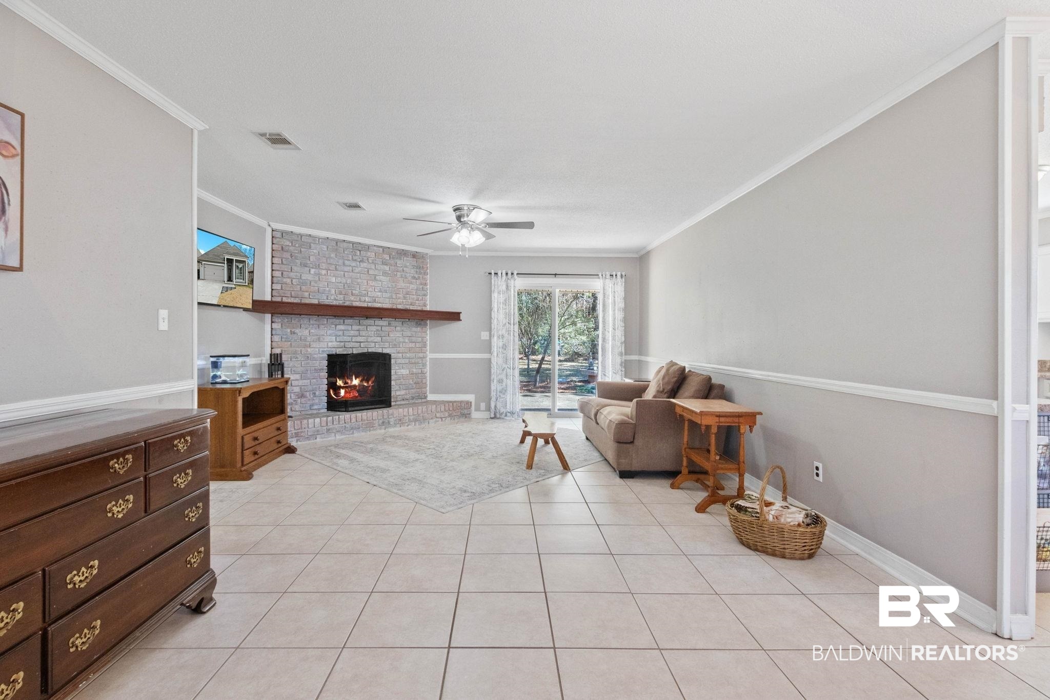 5366 Scanlan Way West Satsuma, AL 36572 - Photo 6 of 43 Living area featuring a brick fireplace, ceiling fan, light tile patterned floors, and ornamental molding