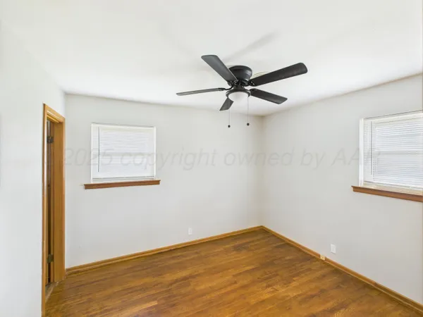 a view of a big room with wooden floor and a ceiling fan