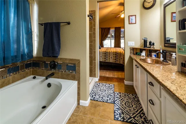 a en suite spacious bathroom with a granite countertop tub and a sink