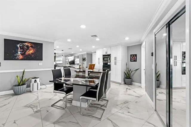a large white kitchen with lots of counter top space a sink and stainless steel appliances