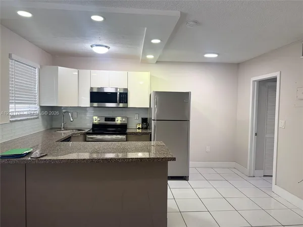 a kitchen with granite countertop a refrigerator a sink and a stove top oven