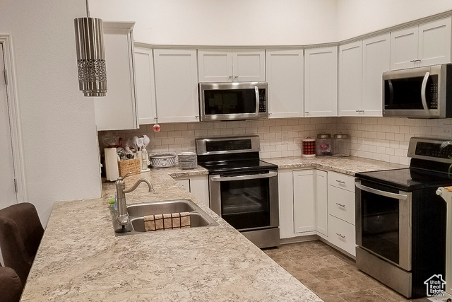 2855 South 1000 West Perry, UT 84302 - Photo 66 of 142 Kitchen featuring stainless steel appliances, decorative backsplash, white cabinetry, and light stone counters