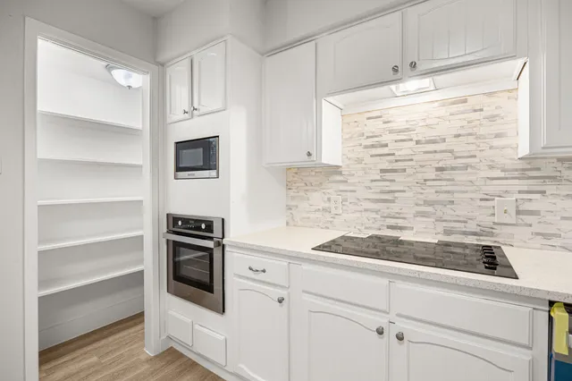 a kitchen with granite countertop white cabinets and appliances