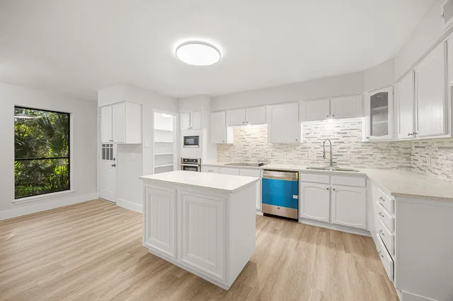 a kitchen with granite countertop white cabinets a sink dishwasher and a stove with wooden floor