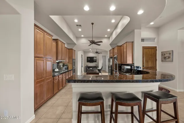 a kitchen with granite countertop a table chairs microwave and refrigerator