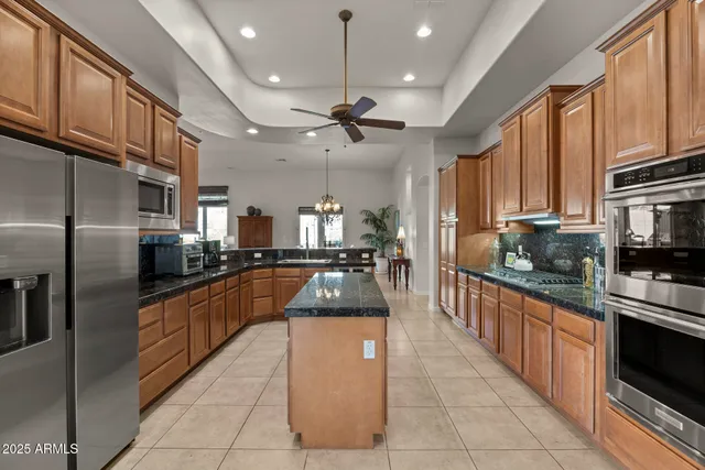 a large kitchen with stainless steel appliances granite countertop a large counter top a stove a sink dishwasher and a refrigerator