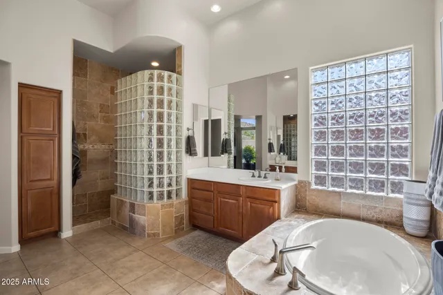 a bathroom with a tub a sink a mirror and a shower