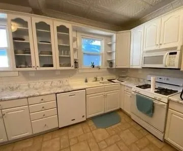 a kitchen with granite countertop white cabinets stainless steel appliances a sink and a window