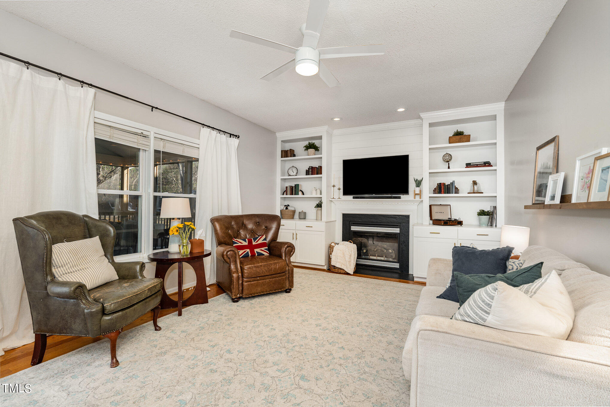 8516 Metronome Lane Raleigh, NC 27613 - Photo 4 of 25 a living room with furniture a fireplace and a flat screen tv