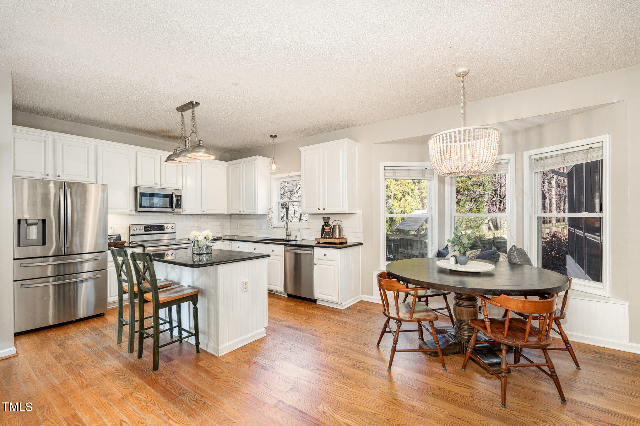 8516 Metronome Lane Raleigh, NC 27613 - Photo 10 of 25 a kitchen with stainless steel appliances wooden floor dining table and chairs