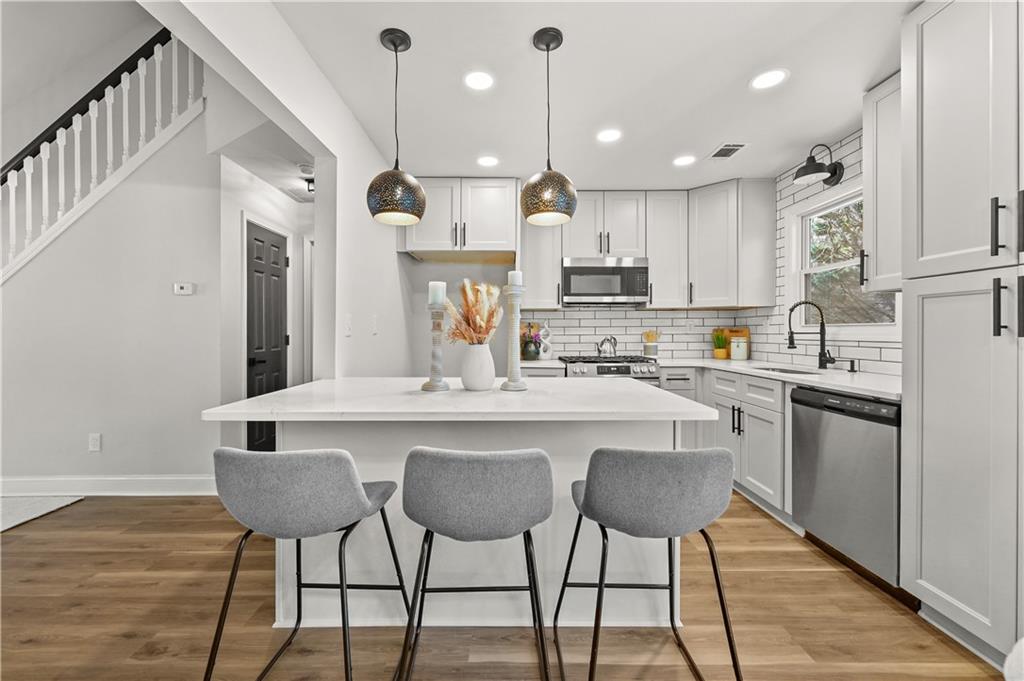 3413 Underwood Road Southeast Conyers, GA 30013 - Photo 12 of 42 a kitchen with stainless steel appliances kitchen island granite countertop a dining table chairs and white cabinets