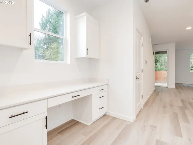 a view of hallway with window and wooden floor