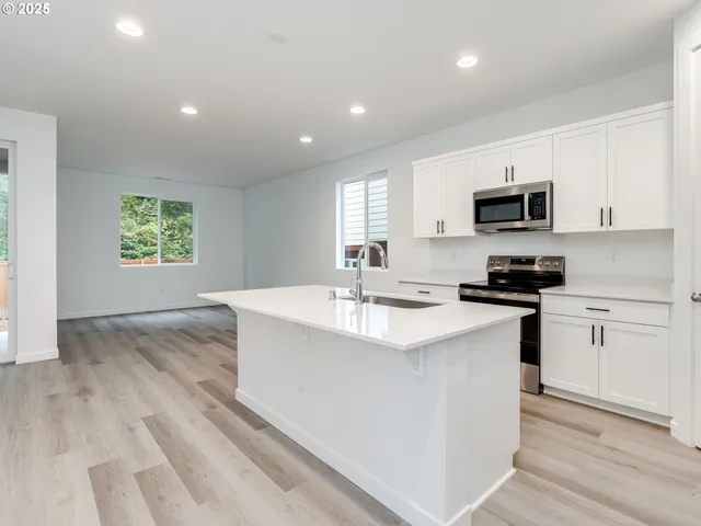 a kitchen with kitchen island granite countertop a sink and a stove top oven
