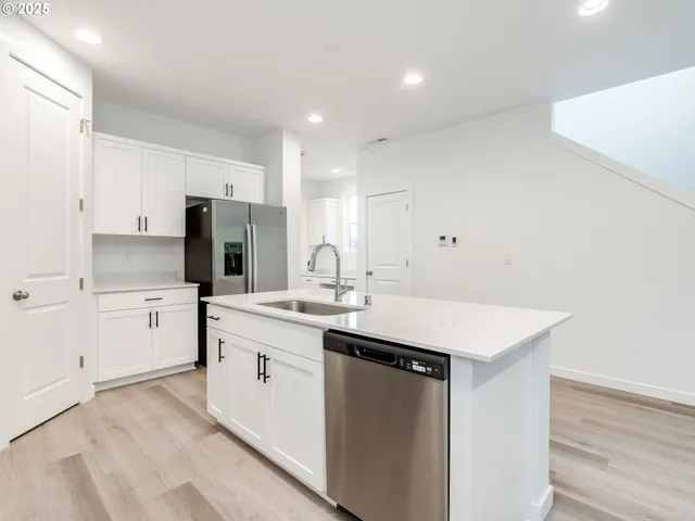 a kitchen with a sink a stove a refrigerator and white cabinets