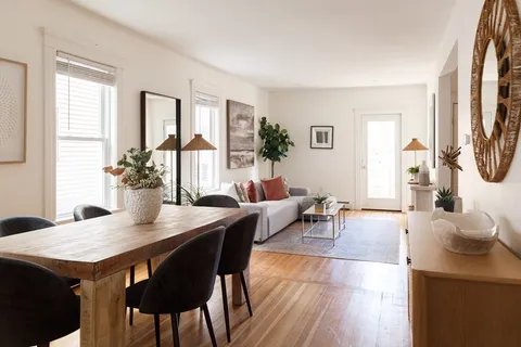 a living room with furniture a large window and wooden floor