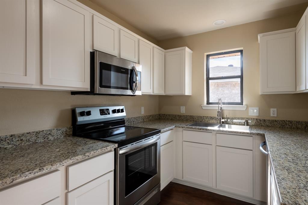 1420 Longview Street Wichita Falls, TX 76306 - Photo 1 of 1 a kitchen with granite countertop white cabinets appliances a sink and a window