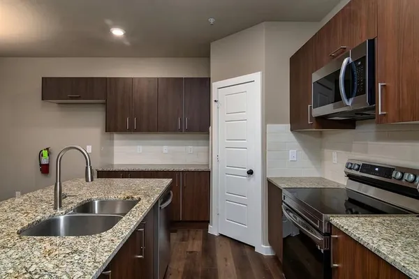 a view of a kitchen with a sink wooden cabinets and stainless steel appliances