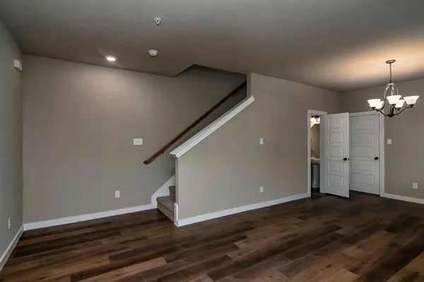 an empty room with a chandelier fan and windows