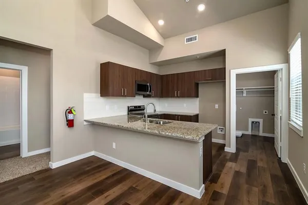 a kitchen with kitchen island granite countertop a sink and steel appliances