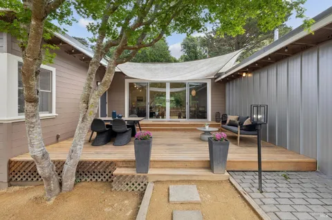 a view of a patio with table and chairs with wooden fence and large trees