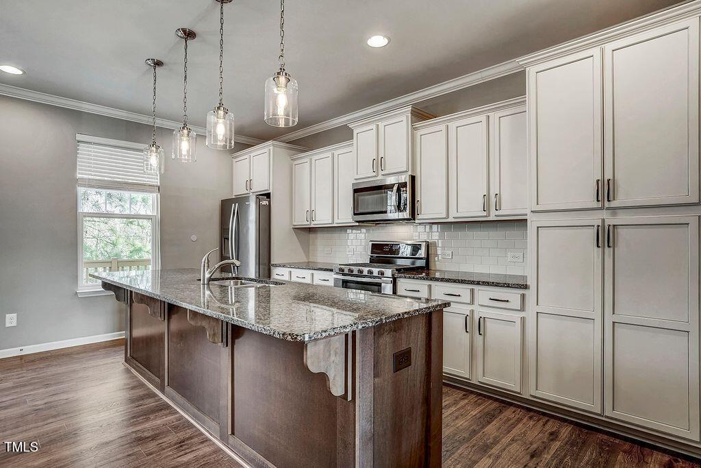 529 Metro Station Apex, NC 27502 - Photo 13 of 28 a kitchen with kitchen island granite countertop a sink a counter space appliances and cabinets