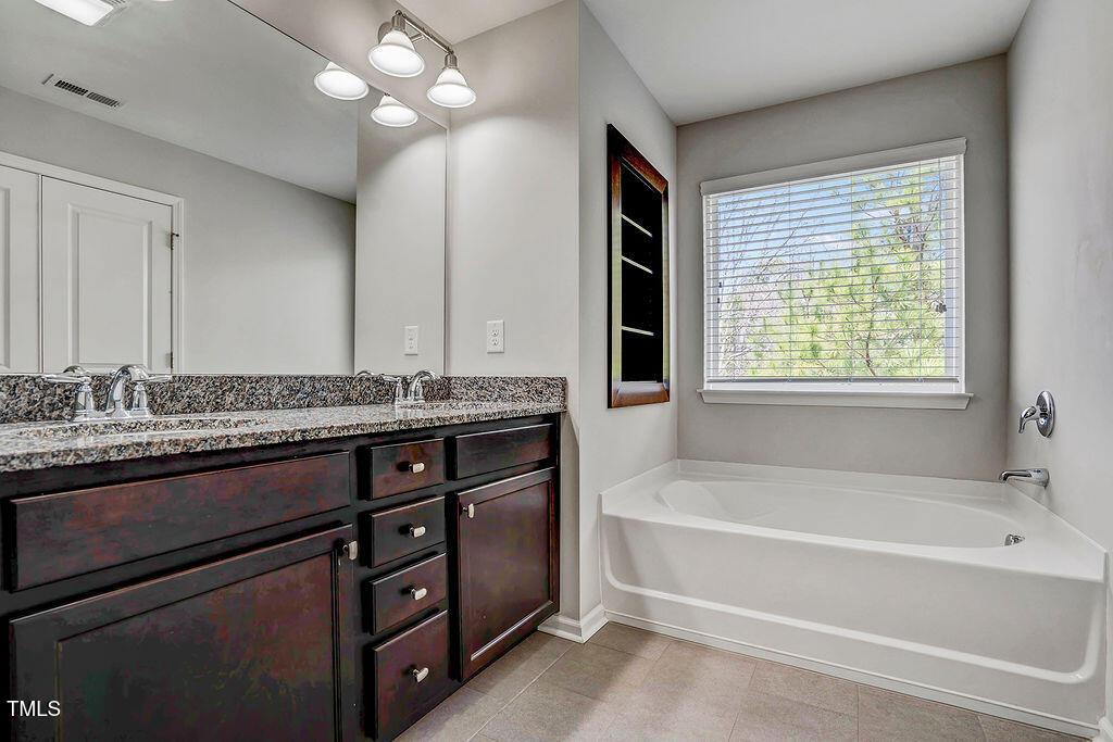 529 Metro Station Apex, NC 27502 - Photo 21 of 28 a bathroom with a tub a sink and a large mirror