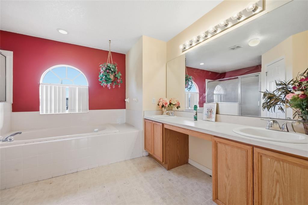 547 Brighton Court Kissimmee, FL 34758 - Photo 28 of 36 a spacious bathroom with a granite countertop tub a double vanity sink and a large mirror