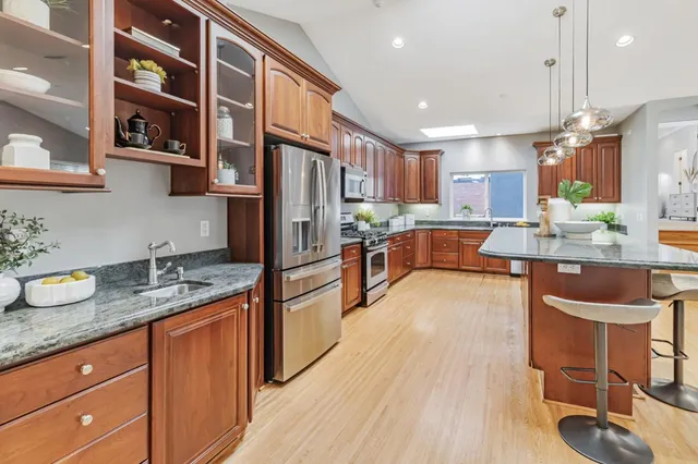 a large kitchen with kitchen island a large counter top space a sink stainless steel appliances and cabinets