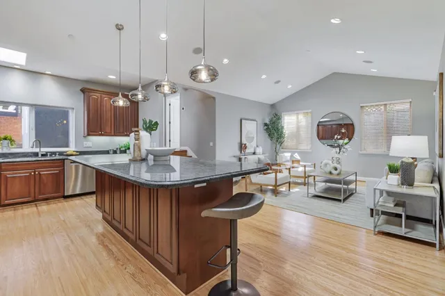 a kitchen with stainless steel appliances granite countertop a sink a stove and a wooden floors