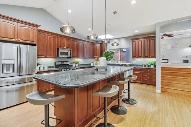 a kitchen with granite countertop a table chairs stove and microwave