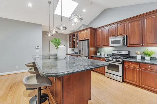 a kitchen with stainless steel appliances a sink stove and wooden floor