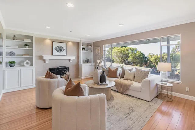 a living room with furniture a large window and wooden floor