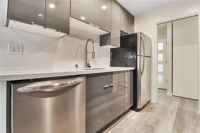 a kitchen with stainless steel appliances granite countertop a refrigerator a sink and a stove