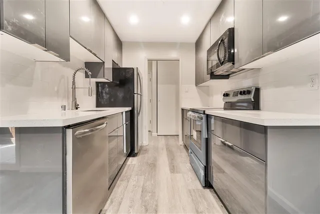 a kitchen with stainless steel appliances granite countertop a refrigerator a stove and a sink