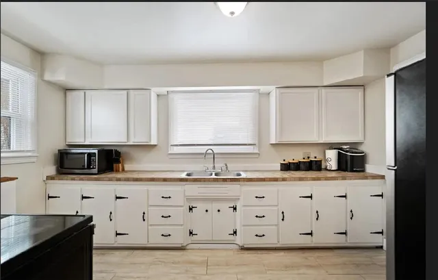 a kitchen with granite countertop white cabinets and refrigerator