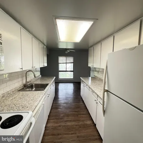 a kitchen with granite countertop a sink a counter space appliances and cabinets