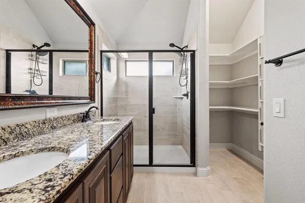 a bathroom with a granite countertop sink a mirror and shower