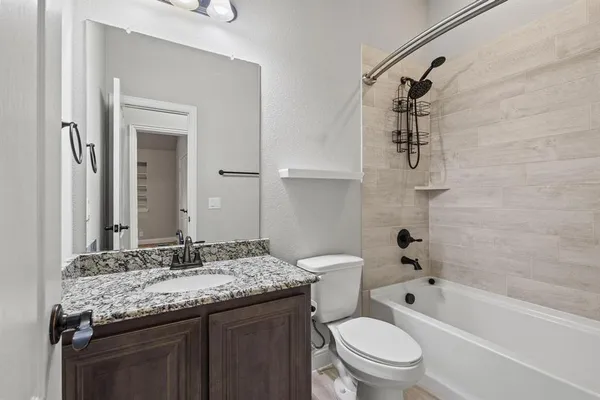 a bathroom with a granite countertop sink a toilet and shower