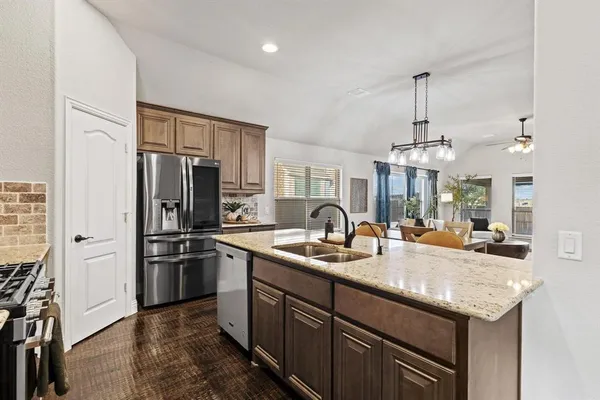 a kitchen with stainless steel appliances granite countertop a sink refrigerator and cabinets