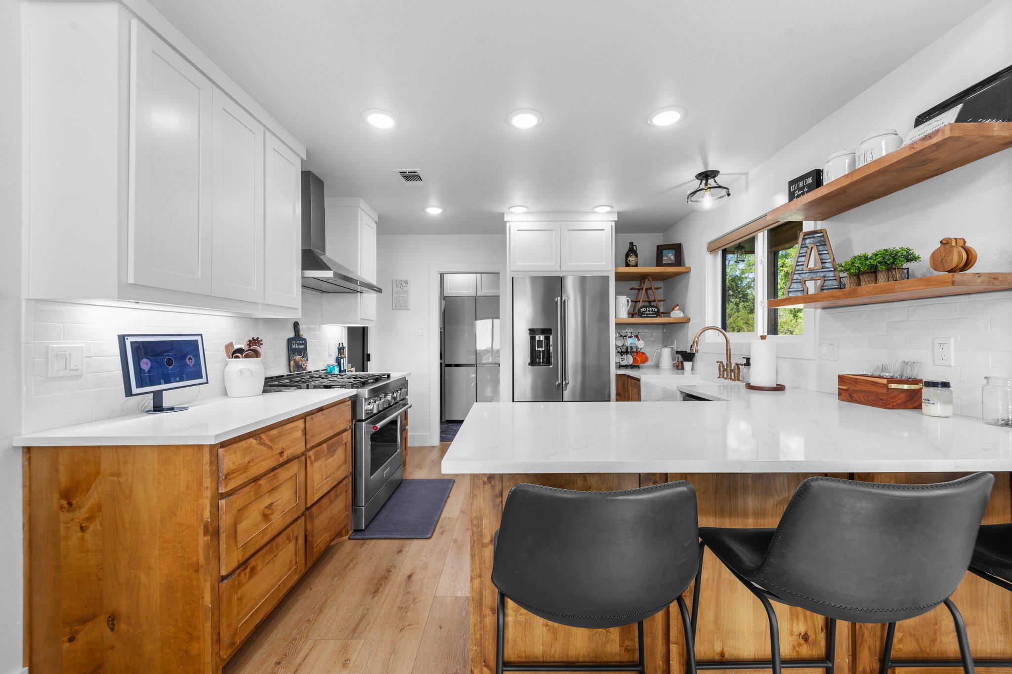 1800 Diamond Ridge Drive Lampasas, TX 76550 - Photo 11 of 40 Dual tone kitchen featuring a peninsula, backsplash, high quality appliances, light stone countertops, and light wood-style floors
