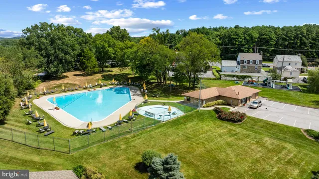 a view of a swimming pool with lawn chairs and a fire pit