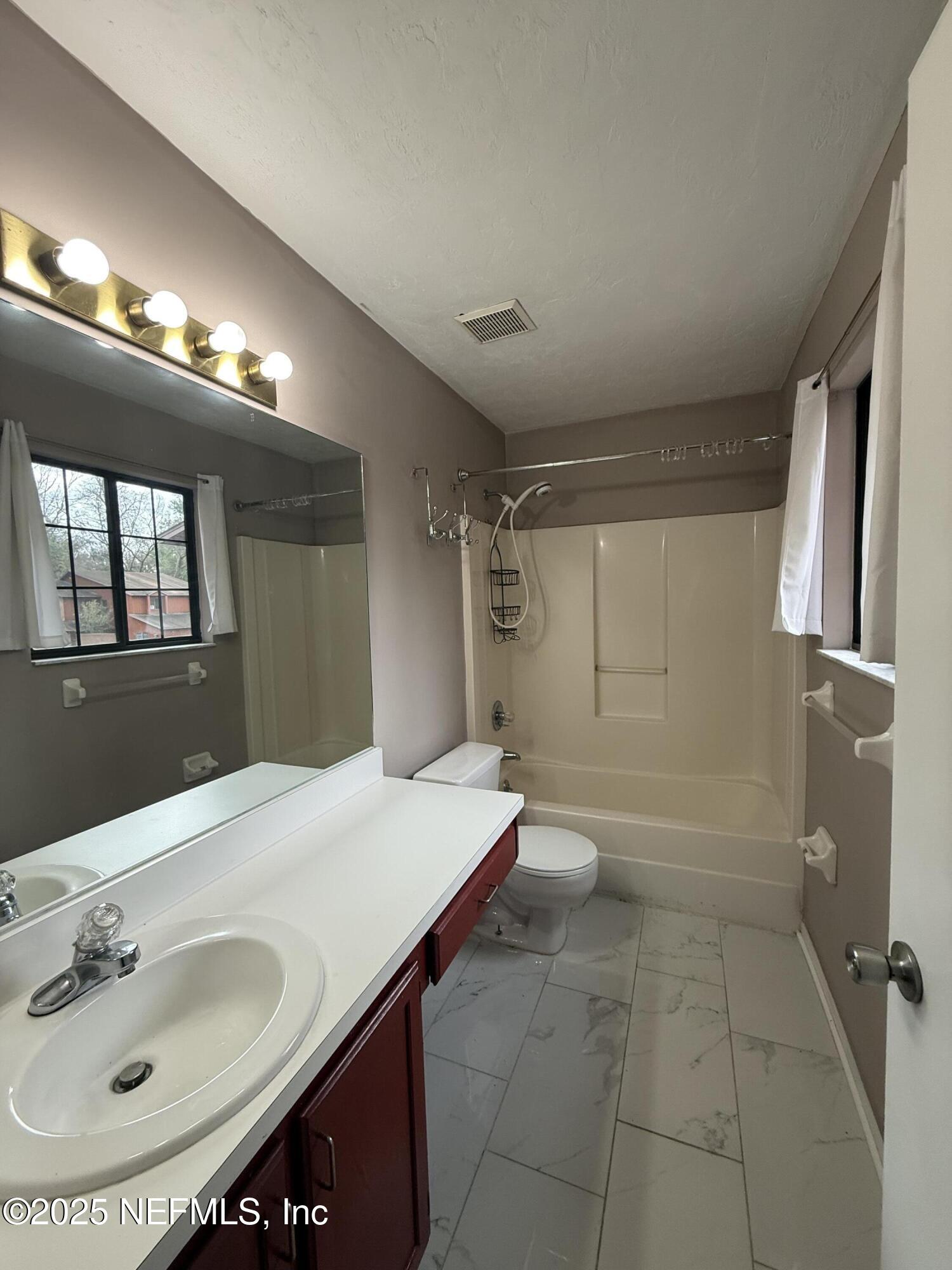 5864 Southwest 8th Place Gainesville, FL 32607 - Photo 6 of 8 a bathroom with a sink a toilet and a mirror