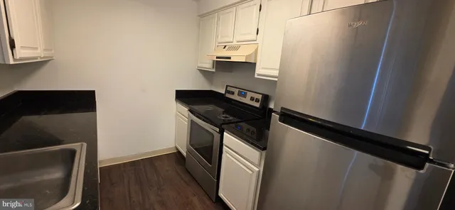 a kitchen with a refrigerator a stove and wooden cabinets