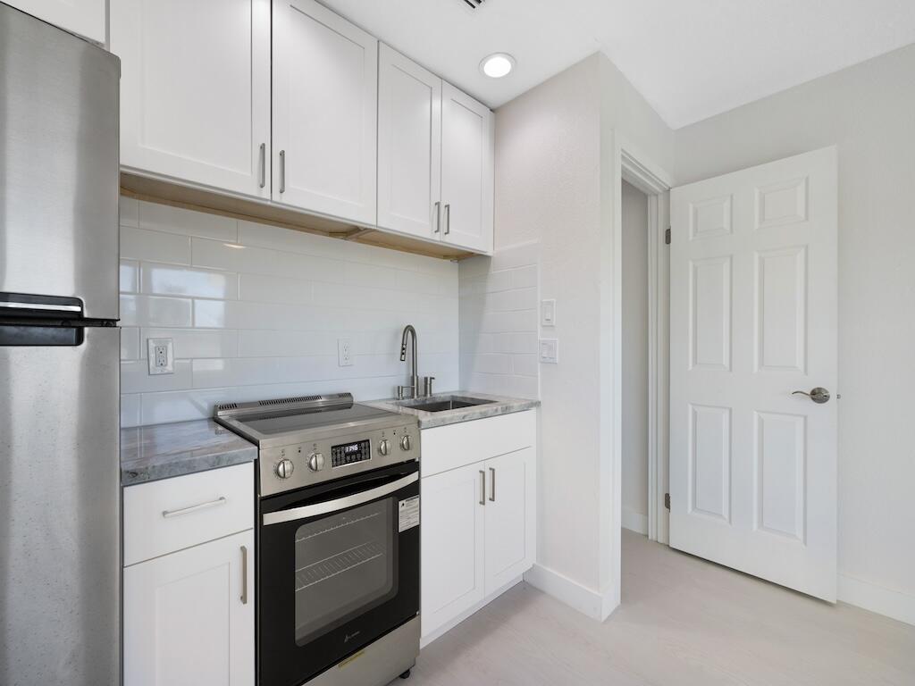 741 Hernando Street Fort Pierce, FL 34949 - Photo 12 of 65 a kitchen with stainless steel appliances granite countertop a stove and a white cabinets