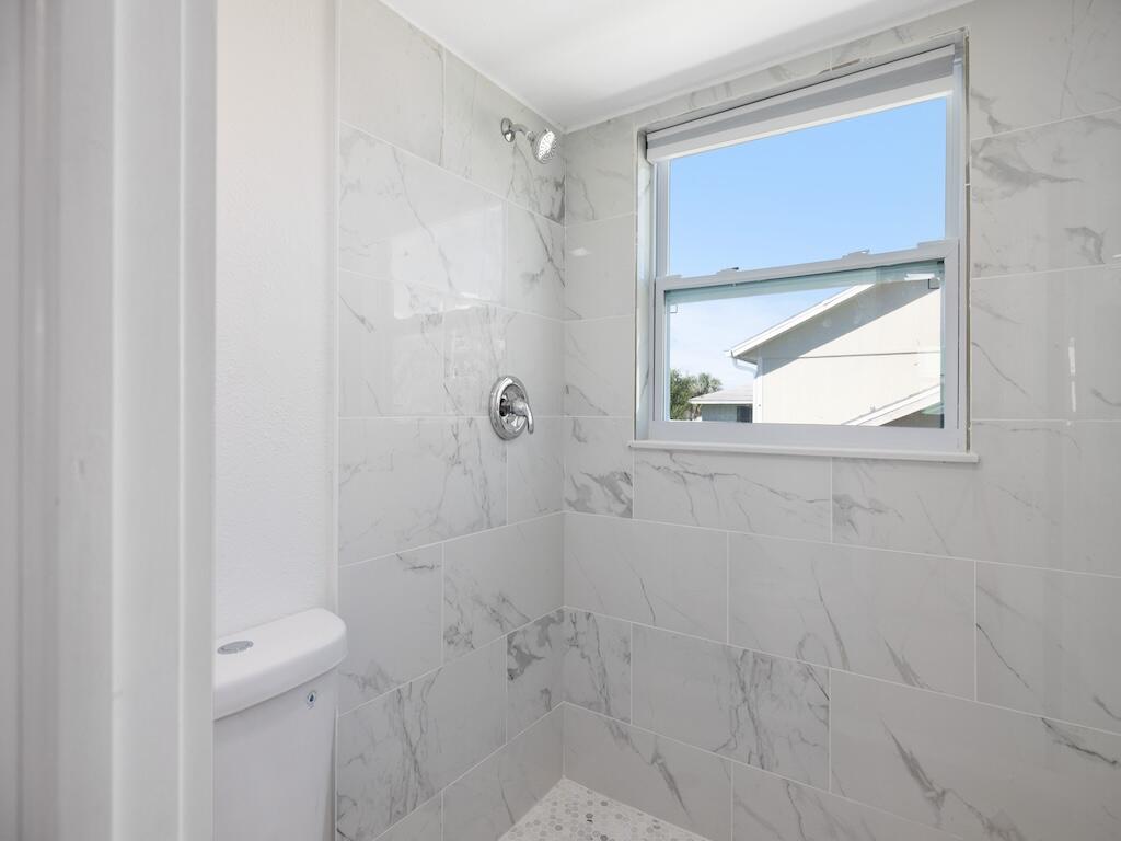 741 Hernando Street Fort Pierce, FL 34949 - Photo 24 of 65 a bathroom with a granite countertop window a toilet and a shower