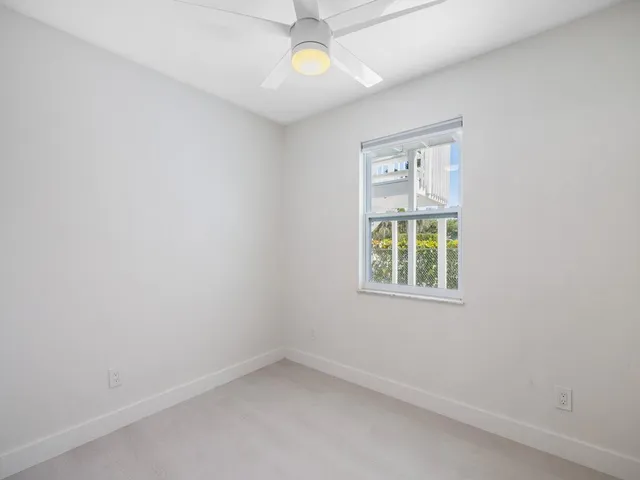 an empty room with a window and a fan