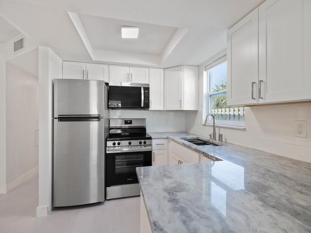 741 Hernando Street Fort Pierce, FL 34949 - Photo 52 of 65 a kitchen with granite countertop a refrigerator stove and microwave